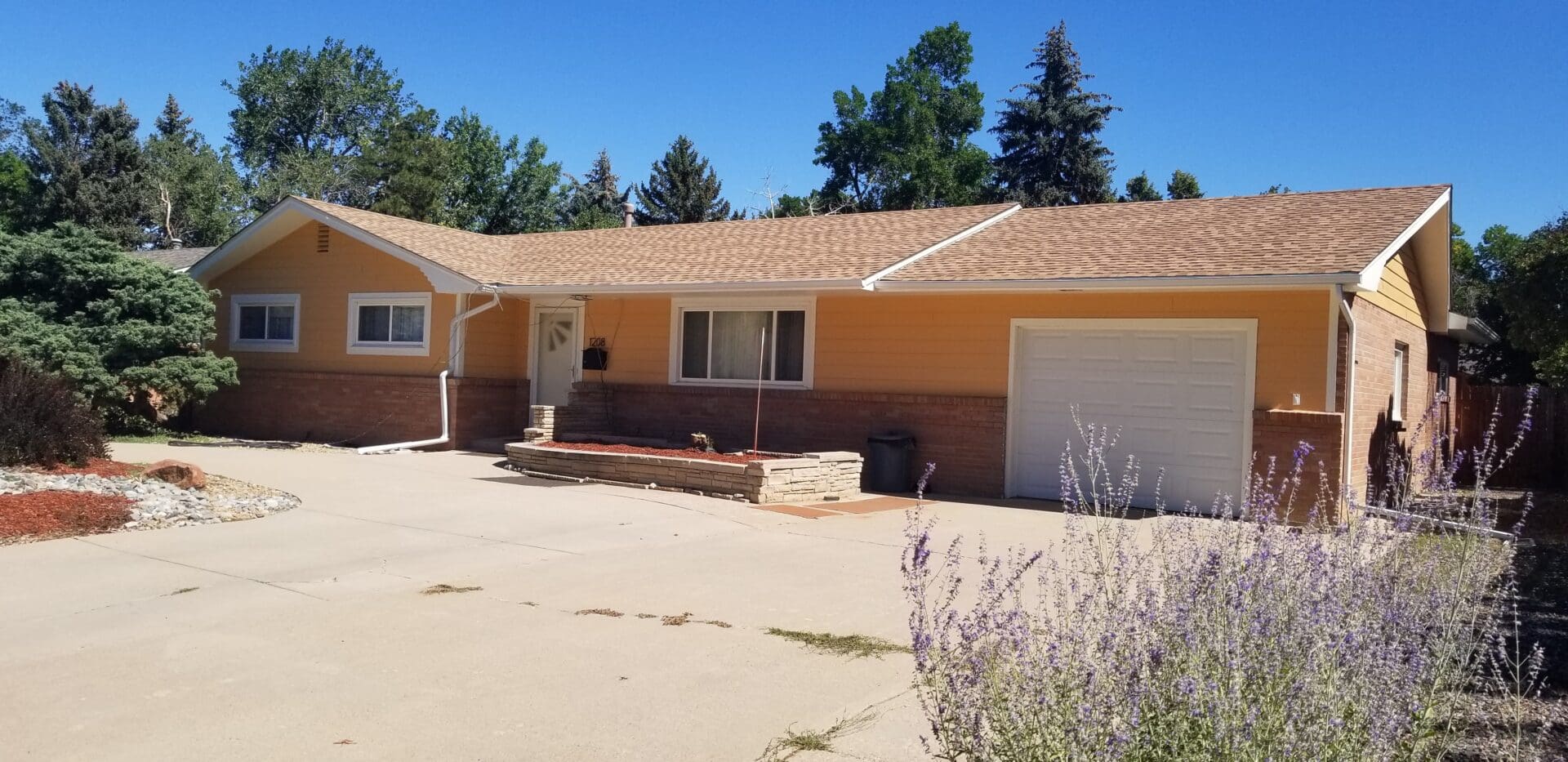 A yellow house with a white door and garage.