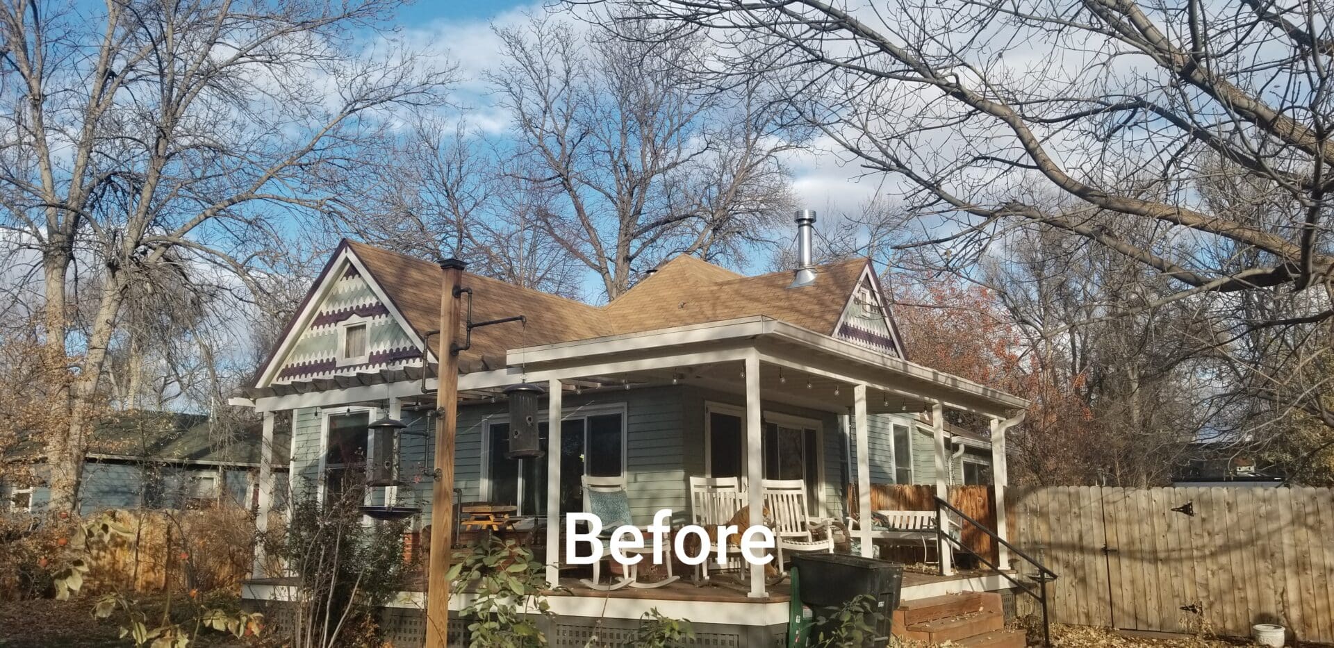 A small house with a porch and a brown roof.