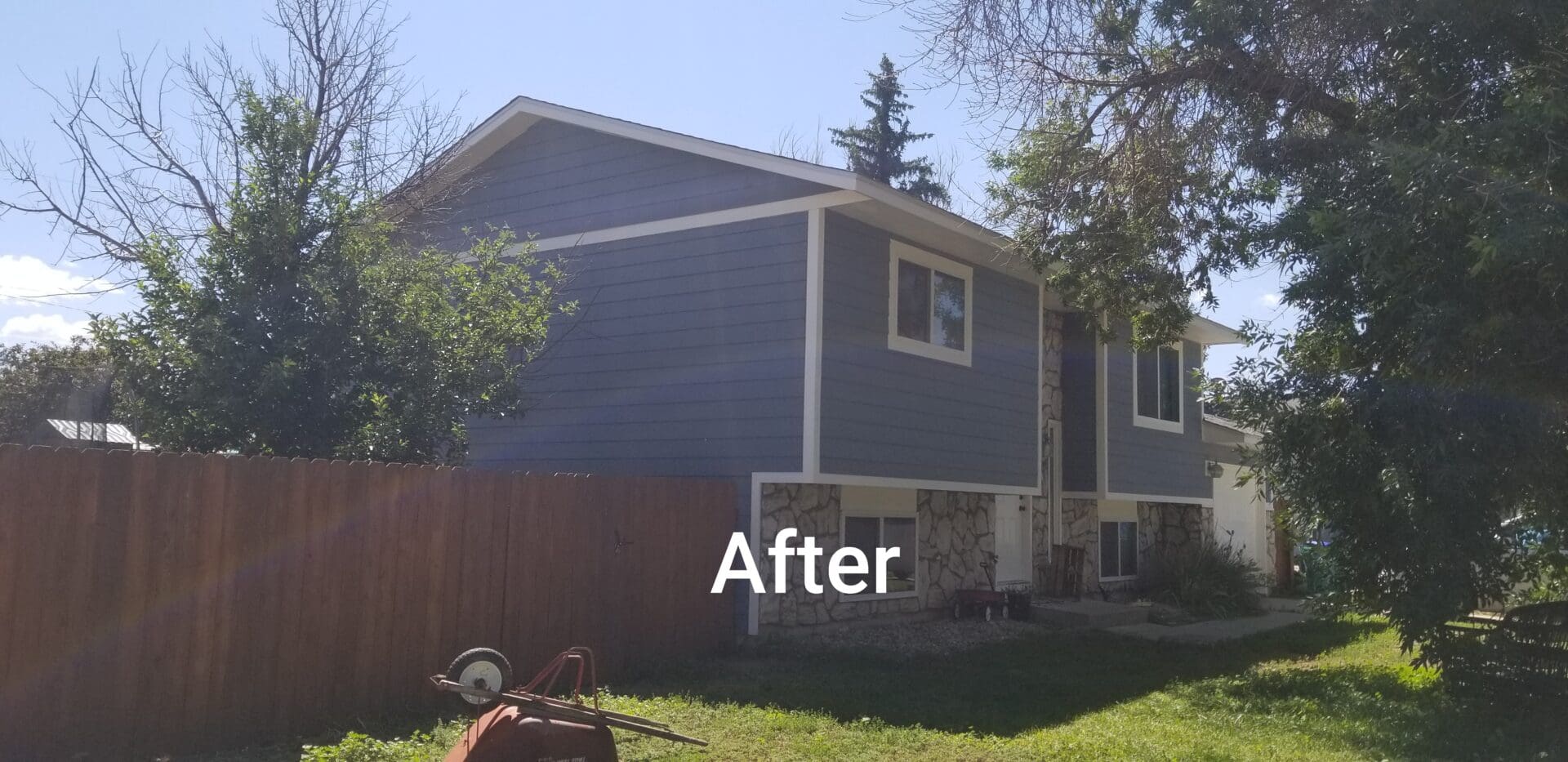 A gray house with white trim and a brown fence.