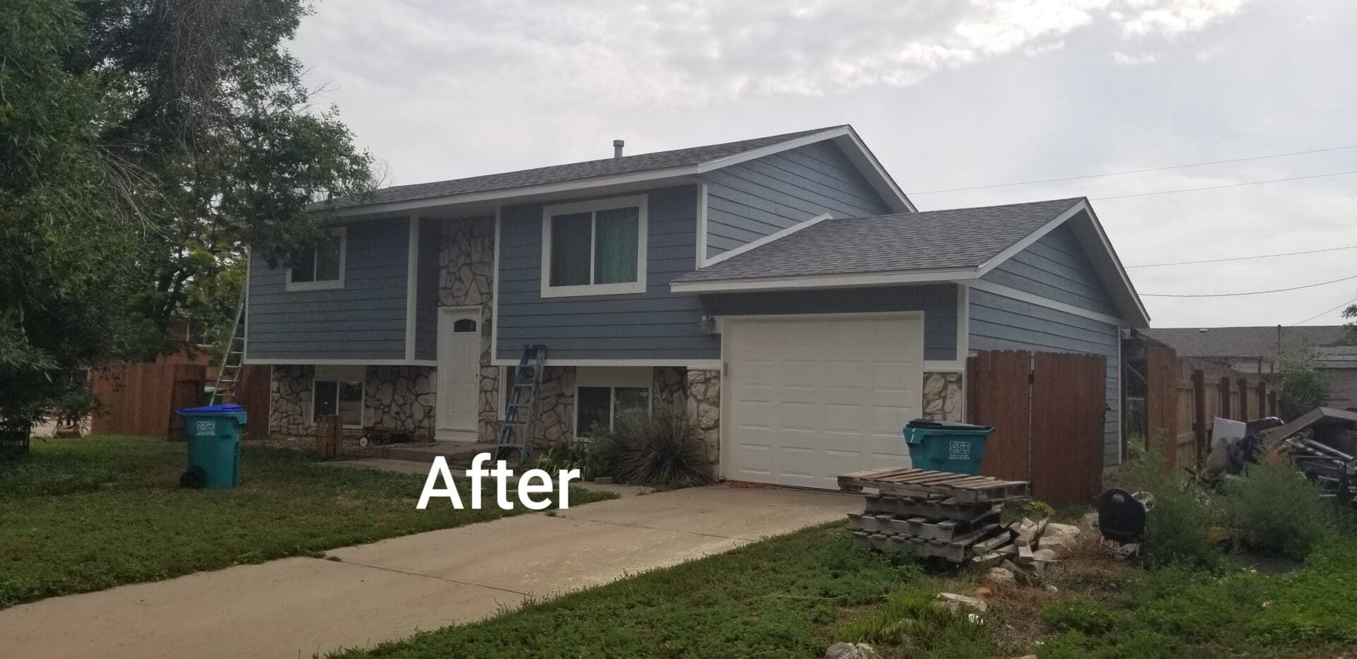 A gray house with white garage door and stone veneer.