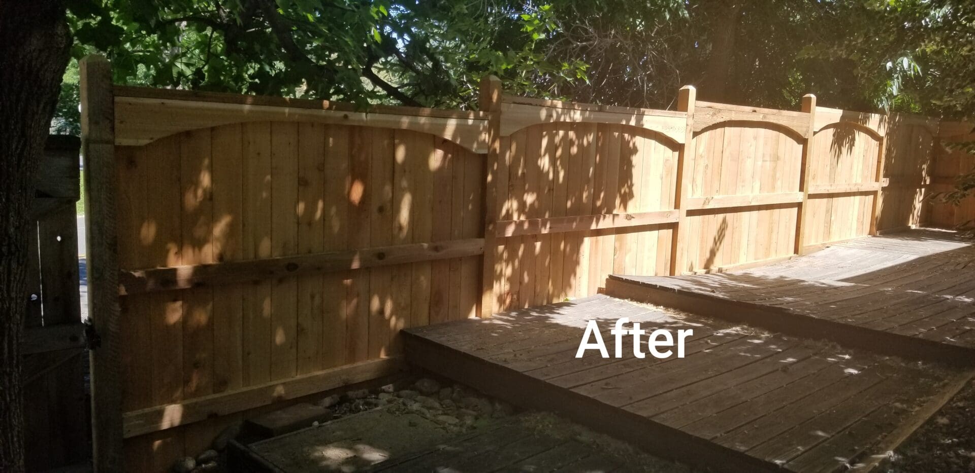 Wooden fence with arched panels and a wooden deck.