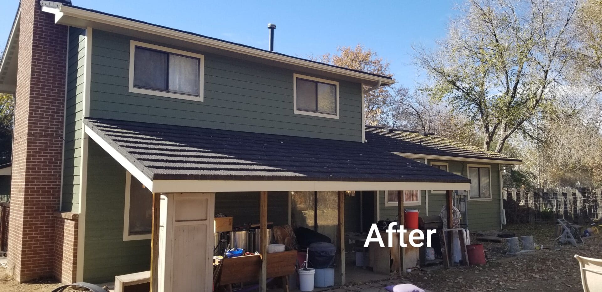 Back of a house with a new roof and green siding.